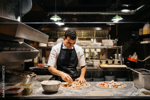 Cook preparing a pizza in a restaurant's kitchen photo