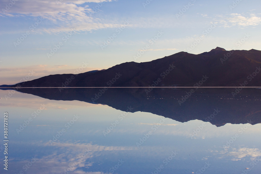 Clouds and mountain are reflecting in the water on salar de Uyuni