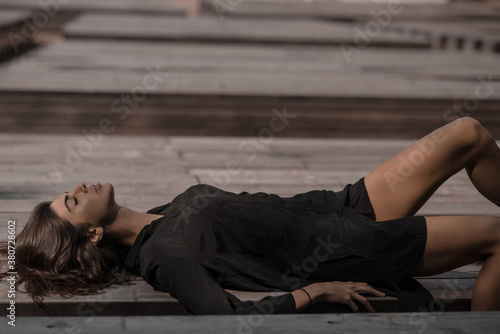 side view of a beautiful dark-haired girl lying on a wooden bench