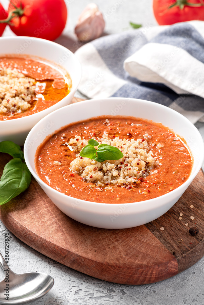 Gazpacho with quinoa. Delicious cold tomato soup with quinoa, peppers, cucumbers, olive oil and spices in a white bowl close-up. Vegan and vegetarian food, Mediterranean cuisine.