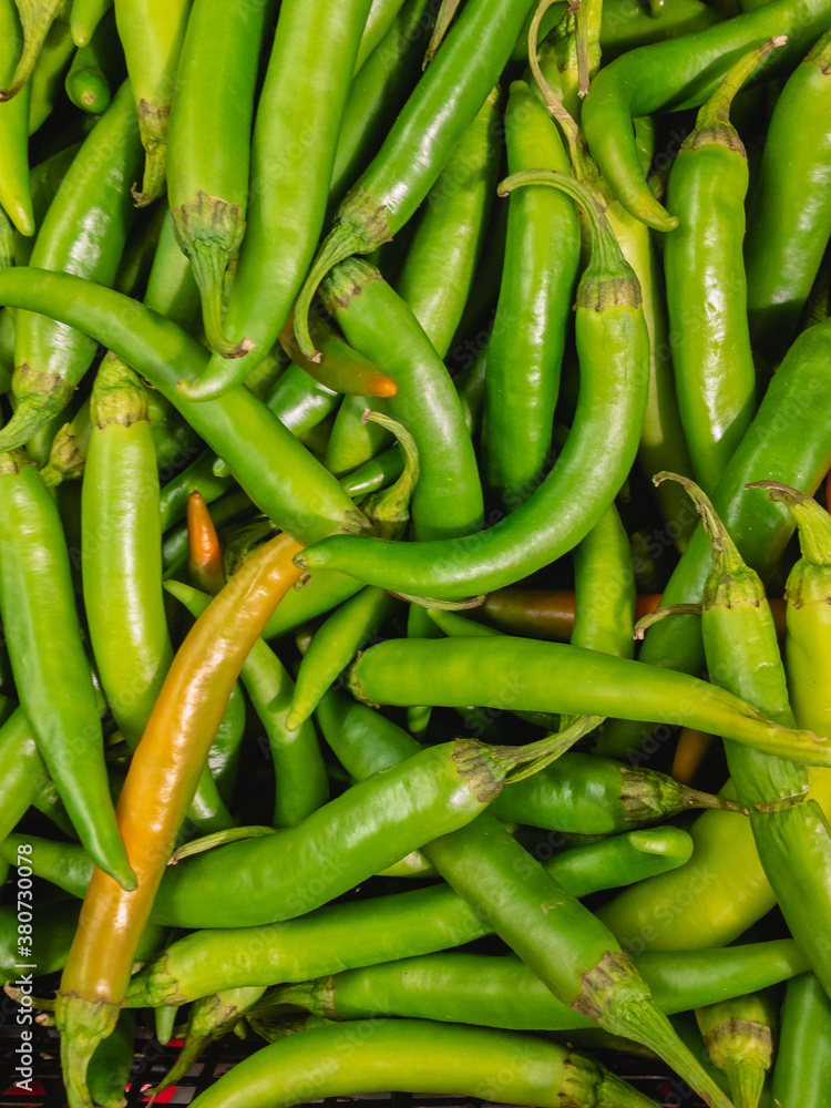 Green chilli pepper (Latin Cаpsicum annuum) lies in a heap for sale in a supermarket. Green chilli pepper (Latin Cаpsicum annuum) lies in a heap for sale in a supermarket.