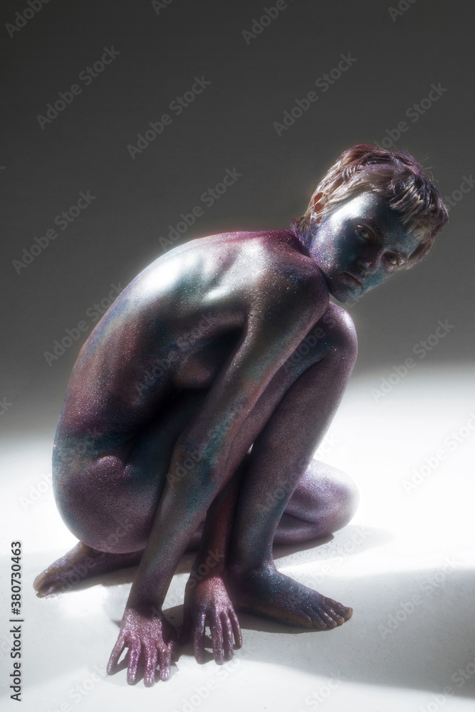 studio portrait of a beautiful nude model with shining body art on her body