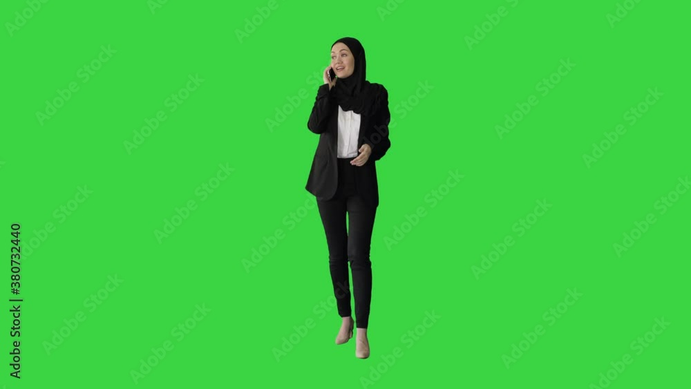 Attractive modern muslim woman walking and talking on cell phone on a Green Screen, Chroma Key. Attractive modern muslim woman walking and talking on cell phone on a Green Screen, Chroma Key.