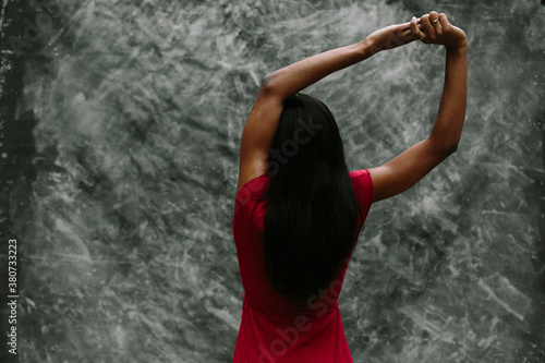 Woman in red stretching her arms over grey background. photo