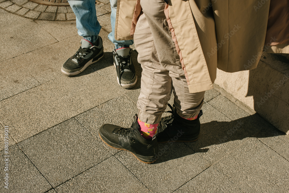 Guys' legs on the ground on the street in sneakers and colorful socks Guys' legs on the ground on the street in sneakers and colorful socks