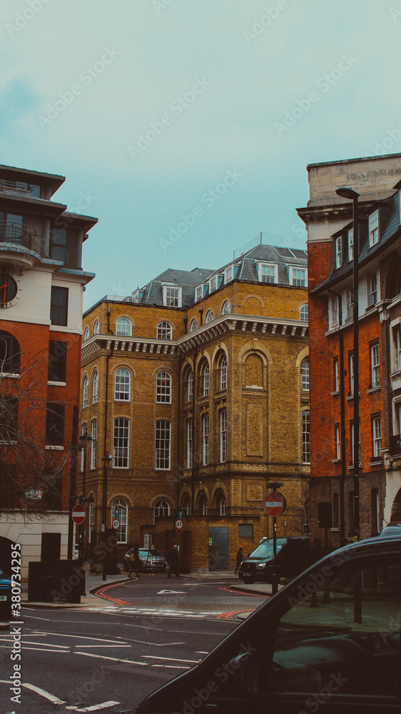 Vertical photograph of buildings from the sidewalk on an afternoon in the City of London.