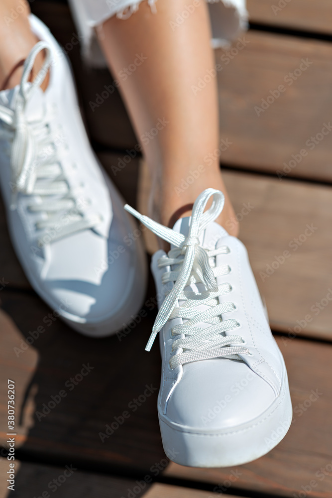 Fragment of the female body. Close-up of legs in white sneakers.