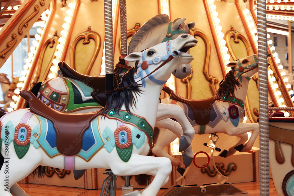 Horses on a traditional fairground Children’s carousel. Wooden horses spin around the post. Joy for children.