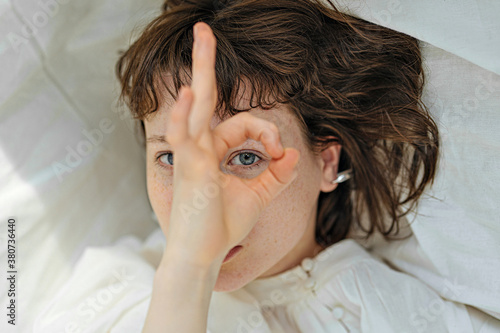 portrait of a girl looking through the okay sign