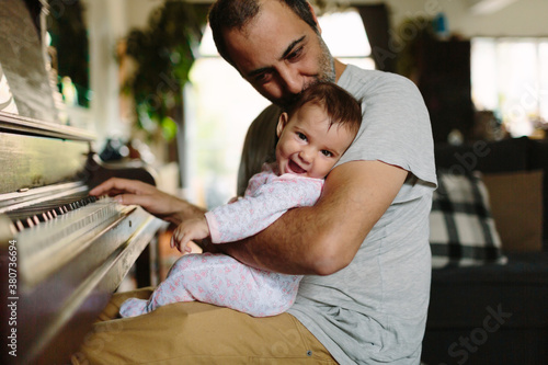 Baby and dad playing piano at home