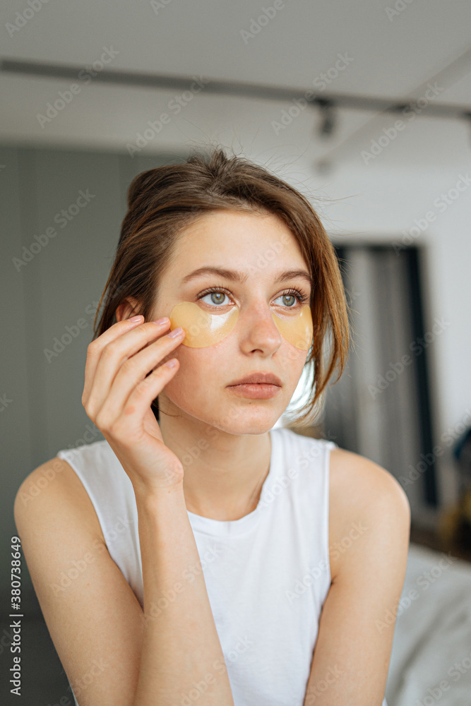 young beautiful woman glues patches under her eyes young beautiful woman glues patches under her eyes