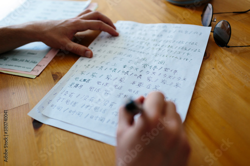 Anonymous hands writing Chinese characters on a paper photo