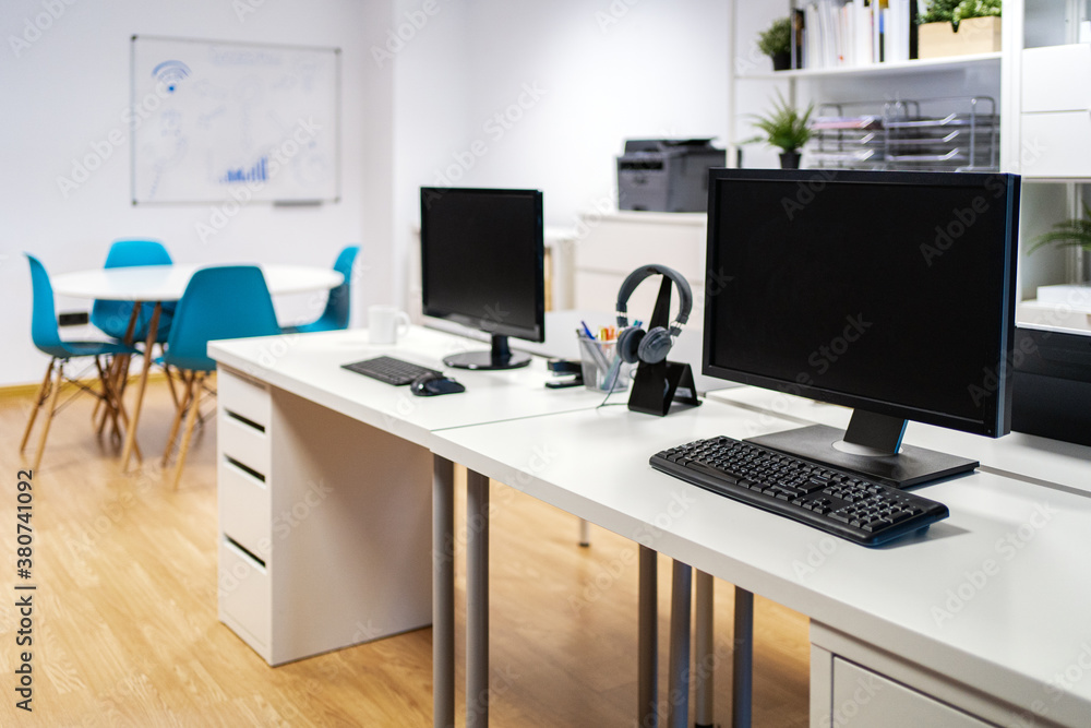 Interior of contemporary coworking space with light furniture and modern computers on desk Interior of contemporary coworking space with light furniture and modern computers on desk