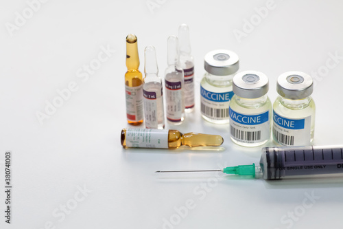 Syringe needle with vaccine bottles and injection vials in closeup view