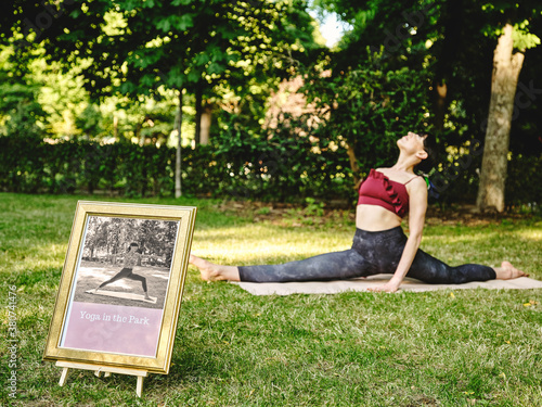 Full body side view of flexible female yoga trainer performing splits or Monkey pose during yoga session on green grass in summer park photo