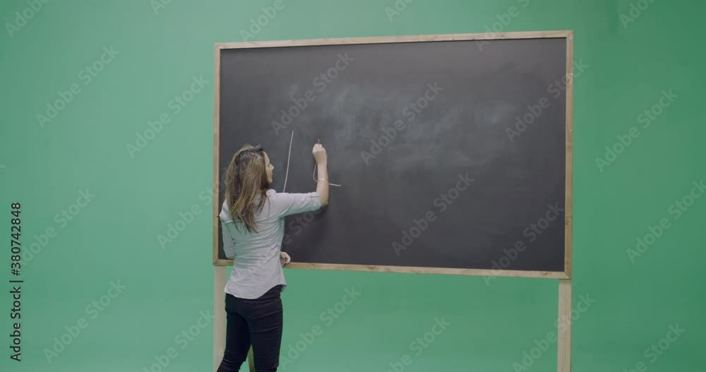 Studio, slow motion, green screen, young female teacher writes on a blackboard, London, UK Studio, slow motion, green screen, young female teacher writes on a blackboard, London, UK