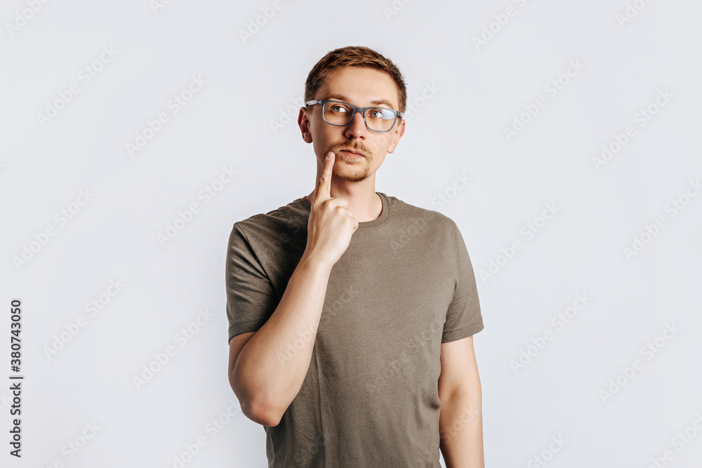 Young handsome man with glasses a brunette beard. Student, worker, businessman posing for photo isolated on gray background. Place for advertising. Young handsome man with glasses a brunette beard. Student, worker, businessman posing for photo isolated on gray background. Place for advertising.