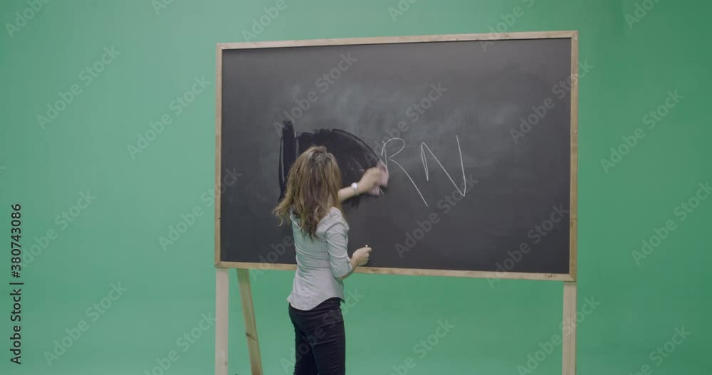 Studio, slow motion, green screen, young female teacher wipes off a vintage blackboard, London, UK Studio, slow motion, green screen, young female teacher wipes off a vintage blackboard, London, UK