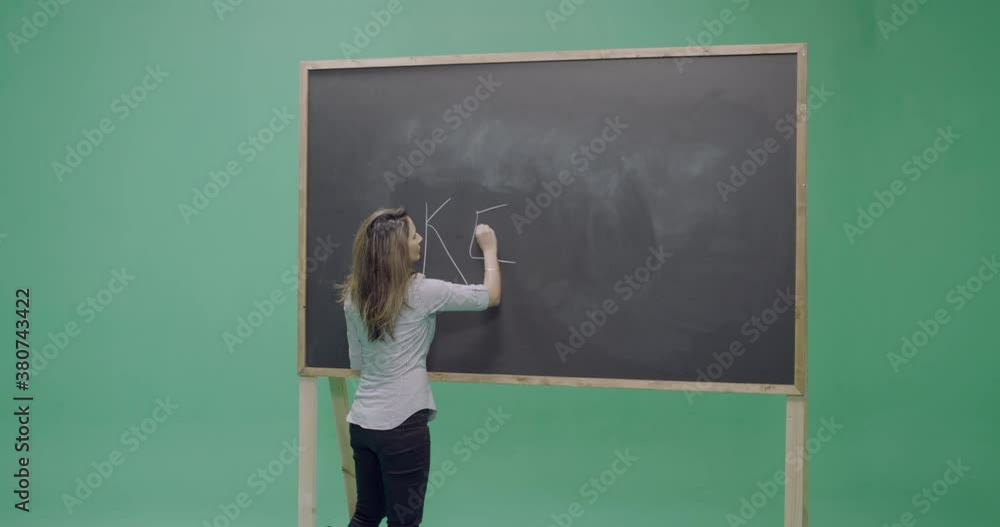 Studio, slow motion, green screen, young female teacher writes on a blackboard, London, UK Studio, slow motion, green screen, young female teacher writes on a blackboard, London, UK