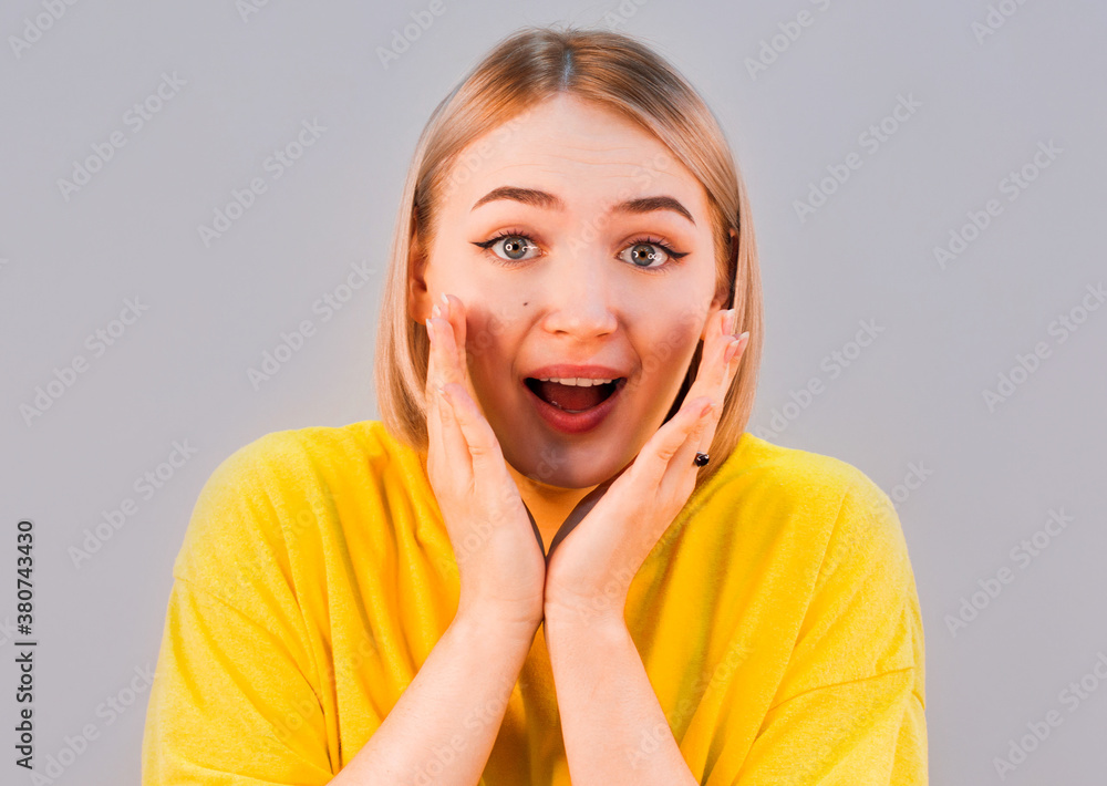 Surprised young woman smiling in studio isolated on gray background Surprised young woman smiling in studio isolated on gray background