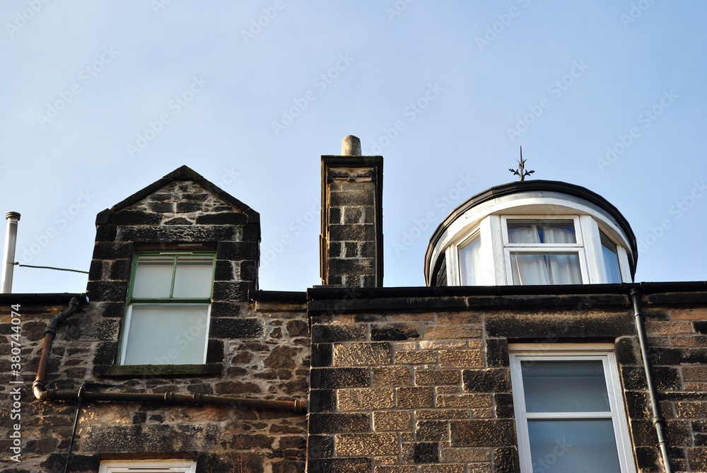 Old Stone Building with Windows & Chimney seen from Below against Blue Sky Old Stone Building with Windows & Chimney seen from Below against Blue Sky