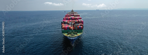 Aerial drone panoramic ultra wide photo of industrial container tanker ship loaded with colourful truck size containers cruising open ocean deep blue sea