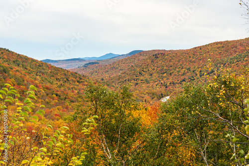 Majestic view of a forested mountain landscape at the peak of fall foliage on a cloudy morning. Pinkham Notch, NH, USA.