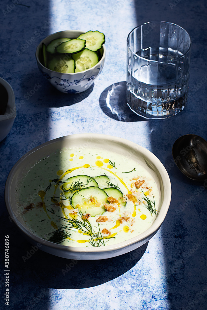 From above cold cucumber and dill soup named Tarator on rustic table with shadow From above cold cucumber and dill soup named Tarator on rustic table with shadow