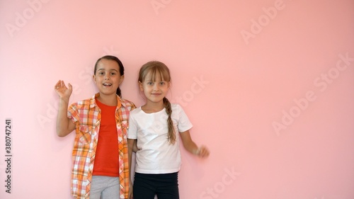 Portrait of two nice-looking attractive charming cute lovely friendly cheerful pre-teen girls isolated on pink pastel background