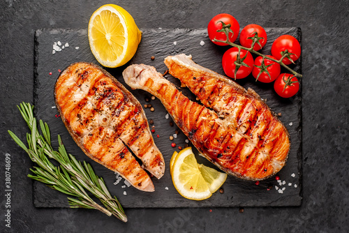 Grilled salmon steak with lemon and rosemary on a stone background 