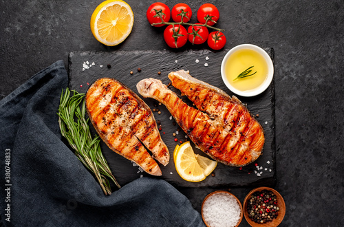 Grilled salmon steak with lemon and rosemary on a stone background	