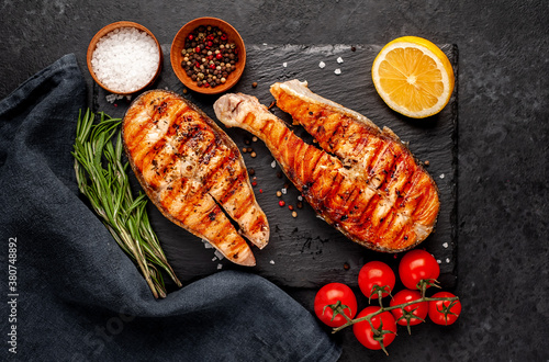 Grilled salmon steak with lemon and rosemary on a stone background 
