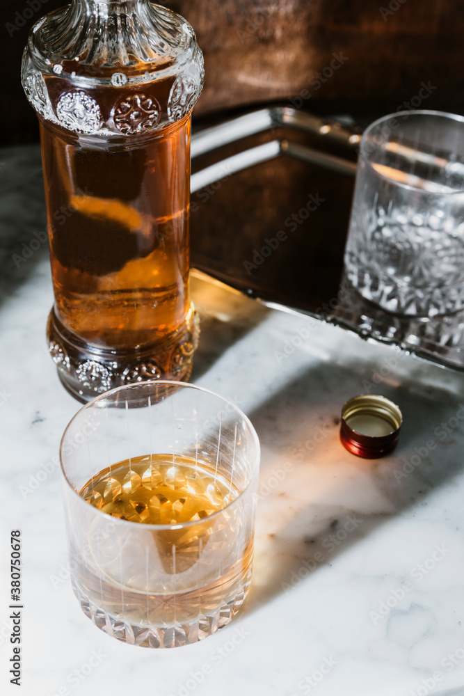 High angle of whiskey in glass and bottle arranged on marble table in bar High angle of whiskey in glass and bottle arranged on marble table in bar