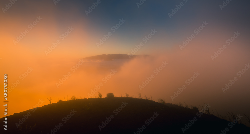 Magnificent view of grassy hill surrounded by thick mist at sundown in highland area Magnificent view of grassy hill surrounded by thick mist at sundown in highland area
