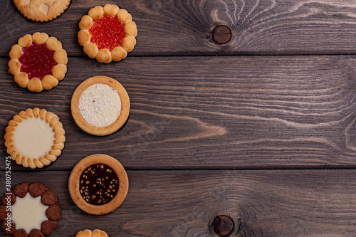 shortbread cookies with various fillings on a brown wooden table. Top view, copy location. Bakery,