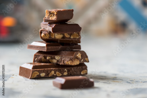 Closeup of stacked broken pieces of chocolate bar with nuts placed on table