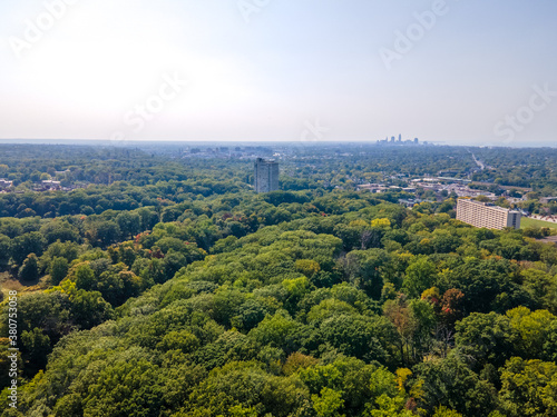 Aerial view of building in trees with downtown skyline in the background