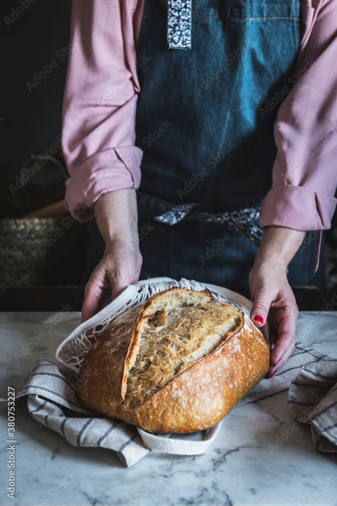 Close-up of a woman holding a loaf of bread with her hands Close-up of a woman holding a loaf of bread with her hands