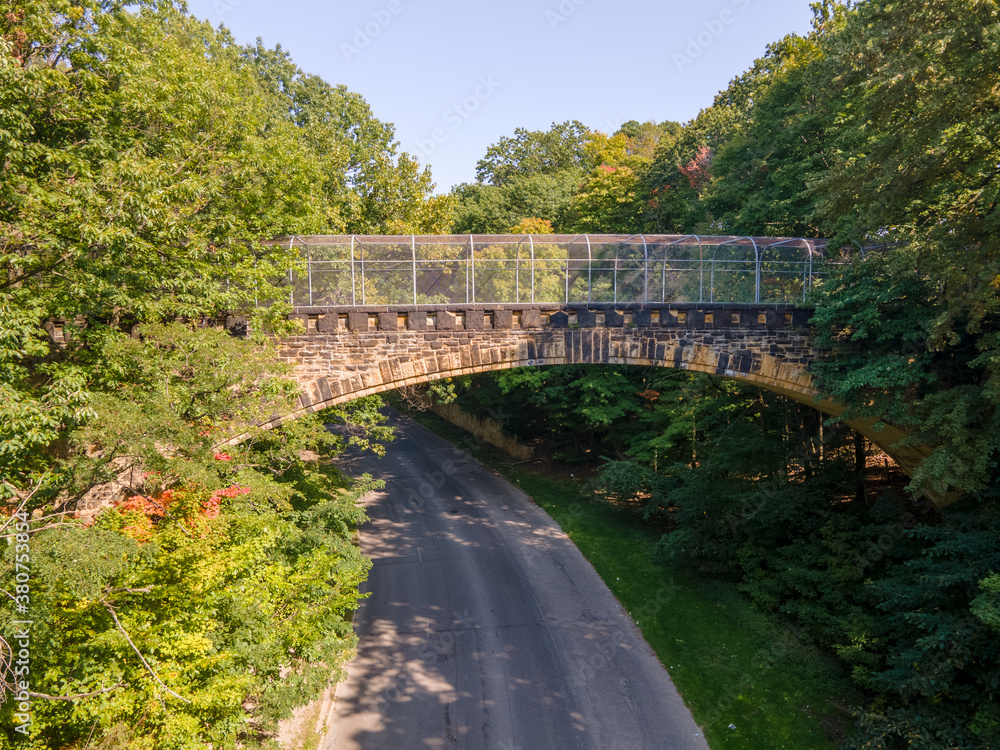 Old stone pedestrian bridge in woods with leaves just starting to change color Old stone pedestrian bridge in woods with leaves just starting to change color