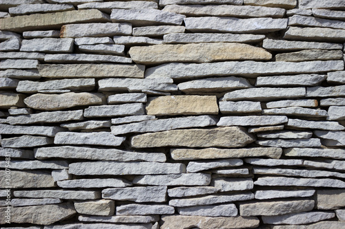 Wall of granite stones, neat masonry. Background, gray-brown texture