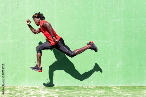 Side view of black sportsman in activewear in moment of jumping during intense workout on sunny day