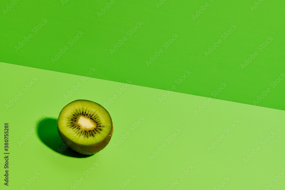© Si And Si/ADDICTIVE STOCK - Half of delicious ripe kiwi fruit placed on green background in modern studio © Si And Si/ADDICTIVE STOCK - Half of delicious ripe kiwi fruit placed on green background in modern studio