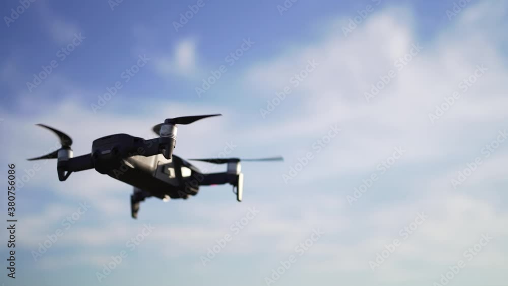 A small drone hovered above the ground against a beautiful sky with clouds. Gadget for remote aerial photography A small drone hovered above the ground against a beautiful sky with clouds. Gadget for remote aerial photography