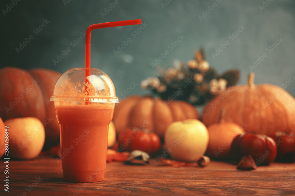 Smoothies in a bottle with a tube on a wooden desk. Carrot juice in bottle with pumpkins. Glass of vegetable juice placed on a table near the pumpkins. Harvest festival, autumn festival.  - obrazy, fototapety, plakaty 