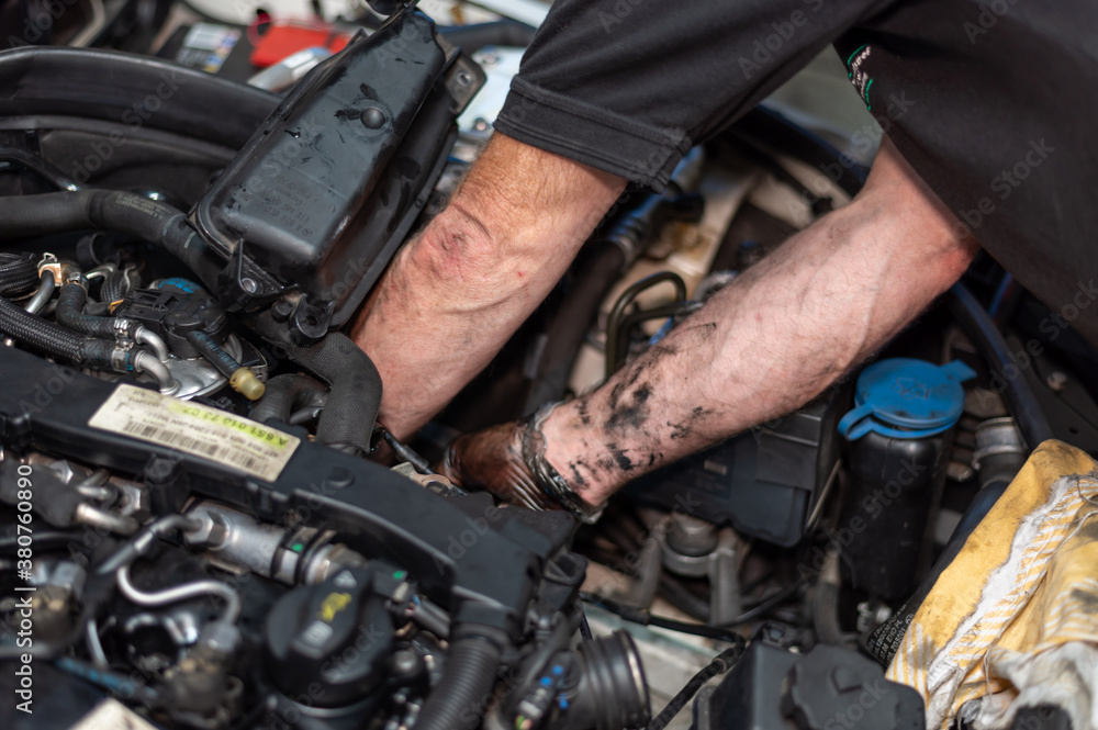 Senior Mechanic working on engine bay repairing a oil leak in home garage Senior Mechanic working on engine bay repairing a oil leak in home garage