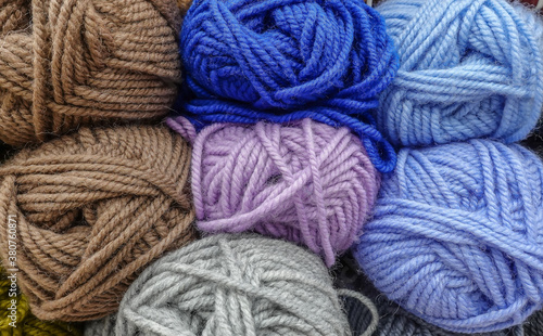 Colorful woolen balls of yarn. Background of colored yarn balls. Needlework. Knitting. Hobby and leisure. Balls of yarn in brown, blue, light grey, light blue, orchid colors.