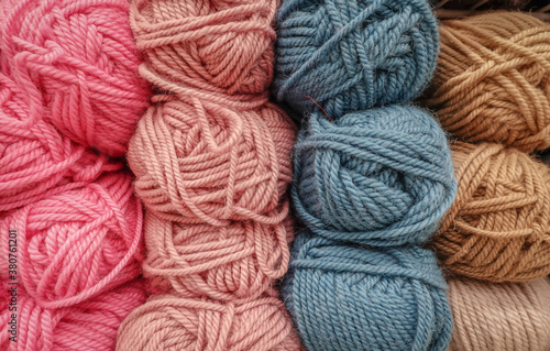 Colorful woolen balls of yarn. Background of colored yarn balls. Needlework. Knitting. Hobbies and leisure. Balls of yarn in pink, blue-grey, salmon and tan colors.