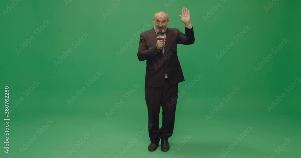 Studio, slow motion, green screen, a mature male reporter waves at camera, London, UK Studio, slow motion, green screen, a mature male reporter waves at camera, London, UK