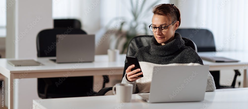 Woman sitting at the desk and using smart phone Woman sitting at the desk and using smart phone