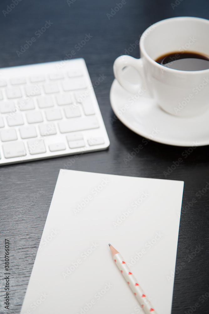 black desk with coffee, keyboard, paper and pen black desk with coffee, keyboard, paper and pen